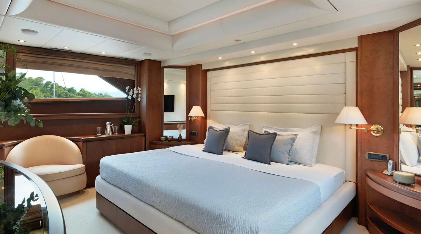 Idylle yacht bedroom with large bed, white linens, and soft blue pillows