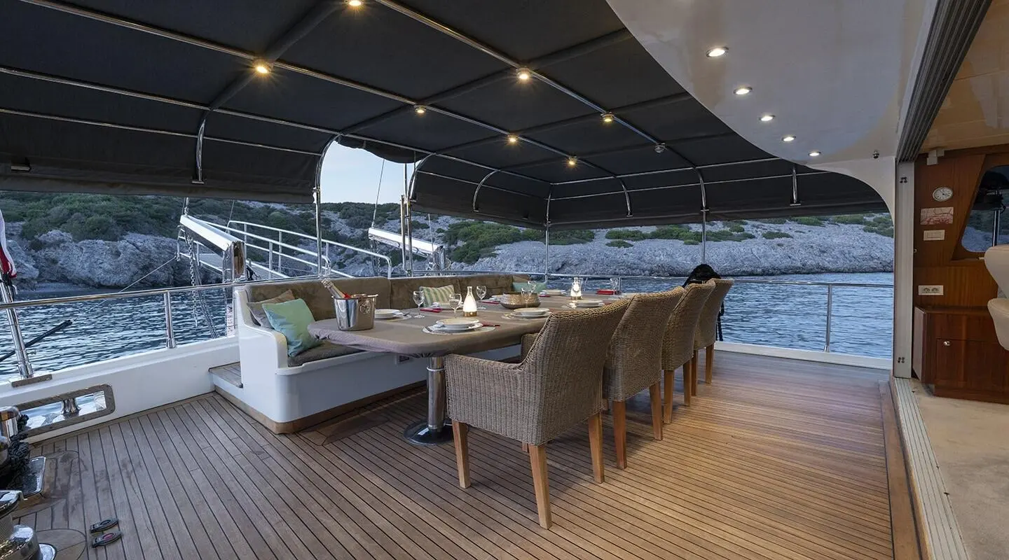 Luxurious yacht Lucky You with a shaded seating area and dining on deck at sunset