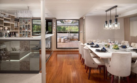 Cristal motor yacht salon with wooden floor, table and chairs in a bright interior