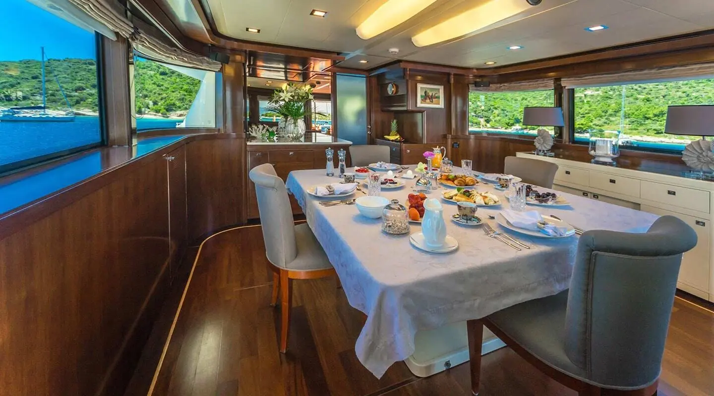 Luxurious wood-paneled dining saloon with a large table set for a meal