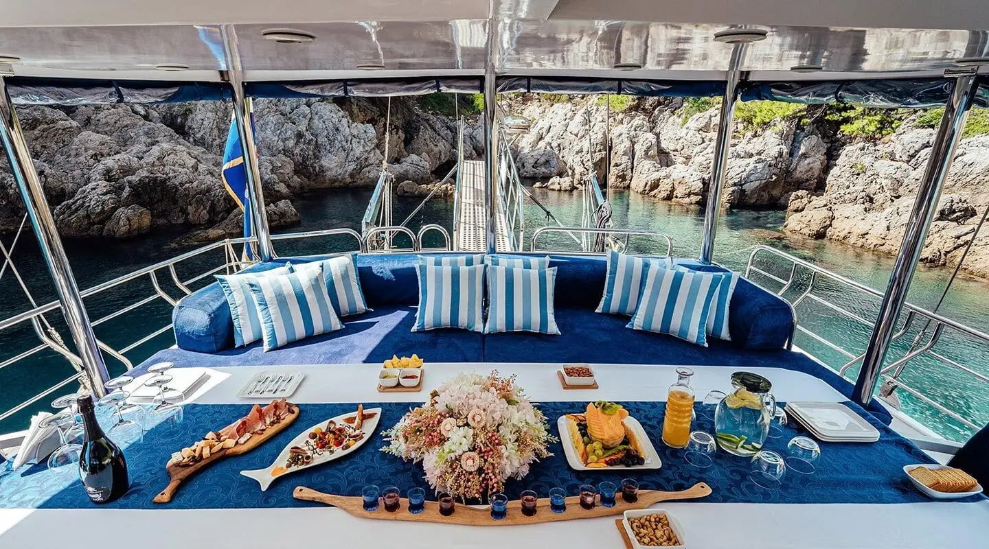 Maske yacht charter: blue cushioned deck seating under shade with decorative items