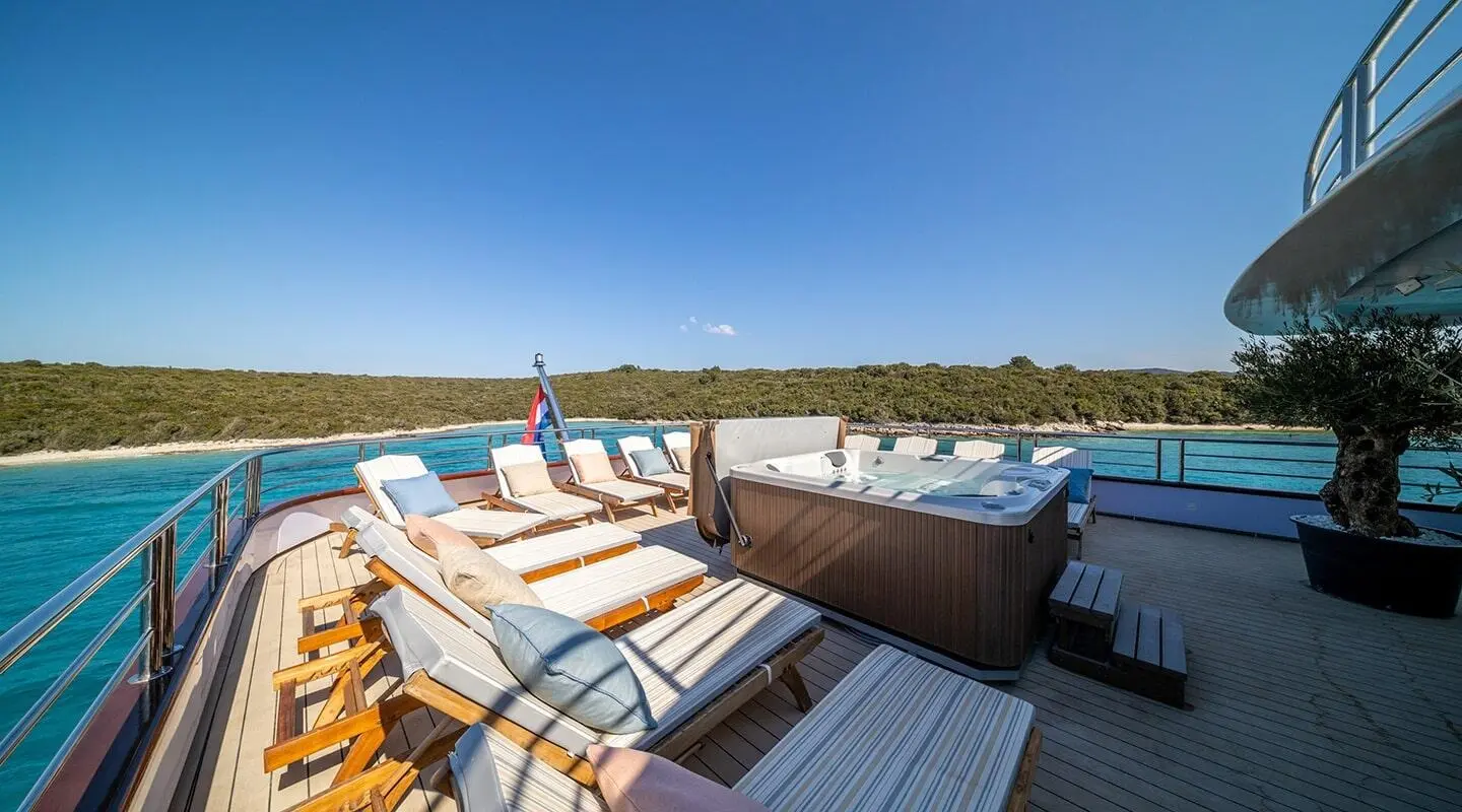 Olimp yacht deck with sun loungers and striped cushions under bright sky