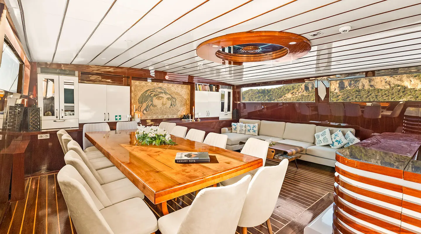 Esma Sultan yacht interior with wooden table, seating, and warm lighting at sunset