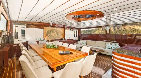 Esma Sultan yacht interior with wooden table, seating, and warm lighting at sunset