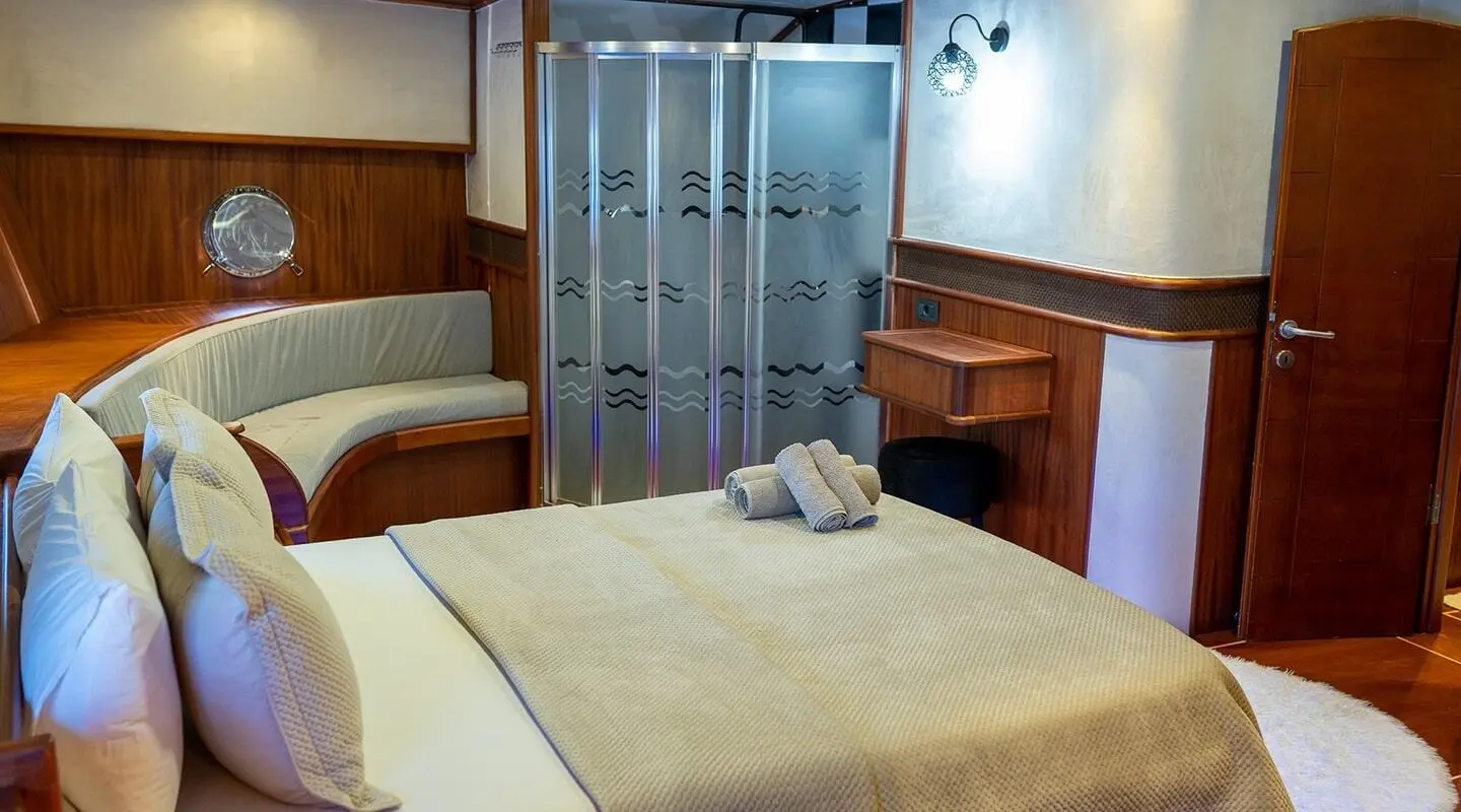 Interior of a luxury yacht cabin with a large bed, wooden panels, and blue lighting