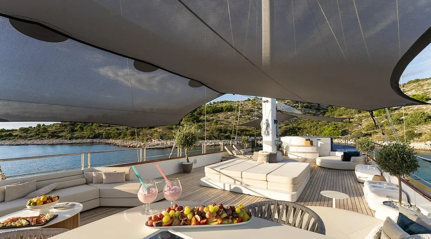 Maxita luxury motor yacht deck with sun loungers, seating, and a shaded aft area