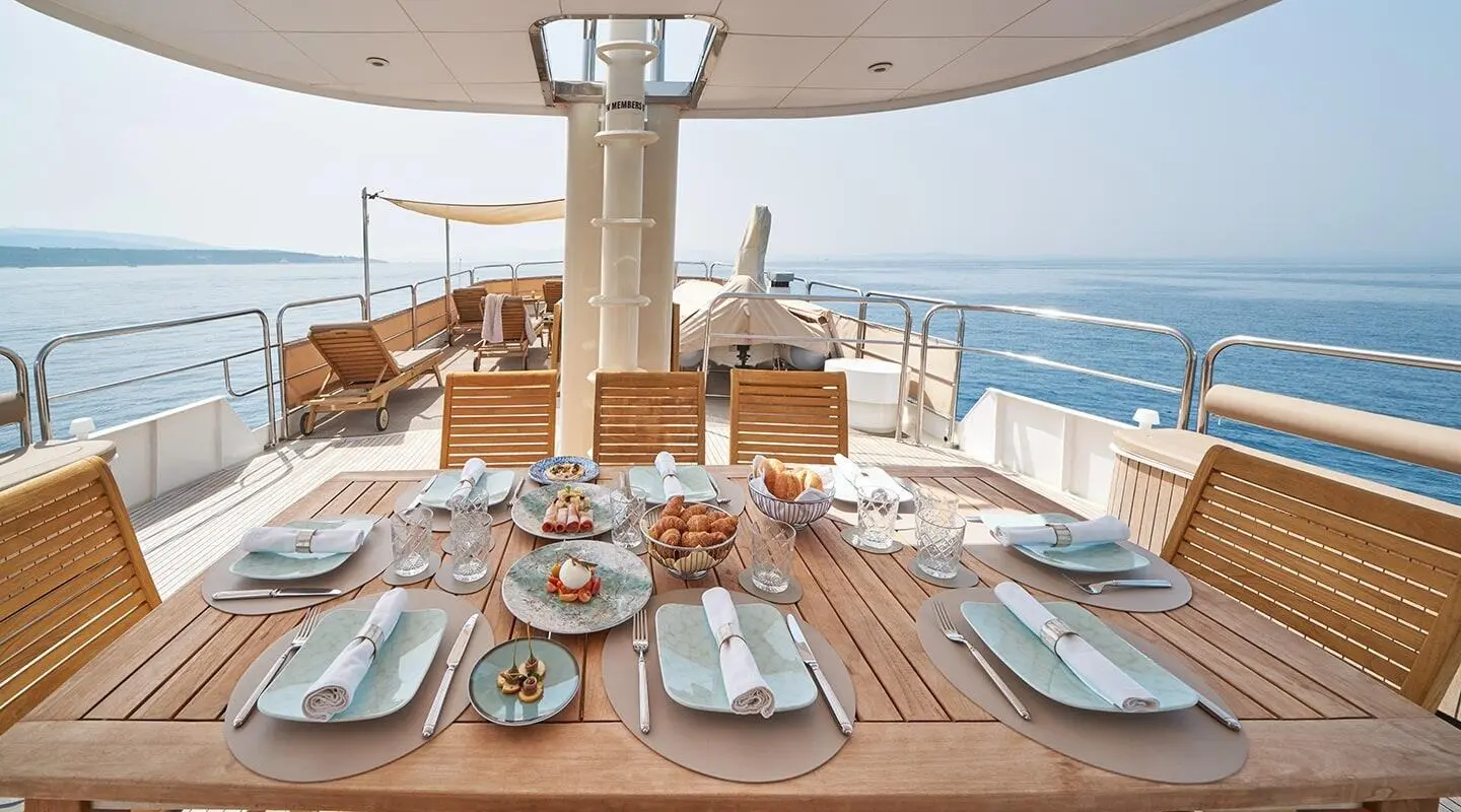 La Perla yacht table setting with glass plates and outdoor decor, sea view