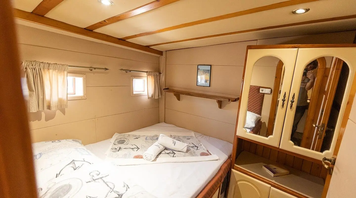 Gardelin yacht interior with a double bed, wood cabinetry, and porthole windows