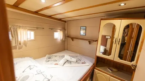 Gardelin yacht interior with a double bed, wood cabinetry, and porthole windows