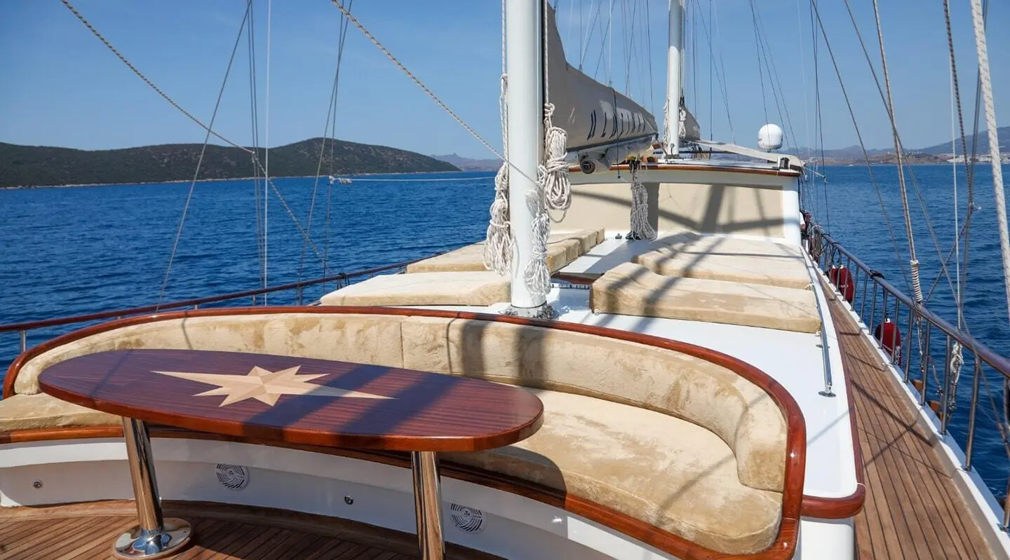 Yacht Ulucinar deck seating area with wooden table aboard at sunset