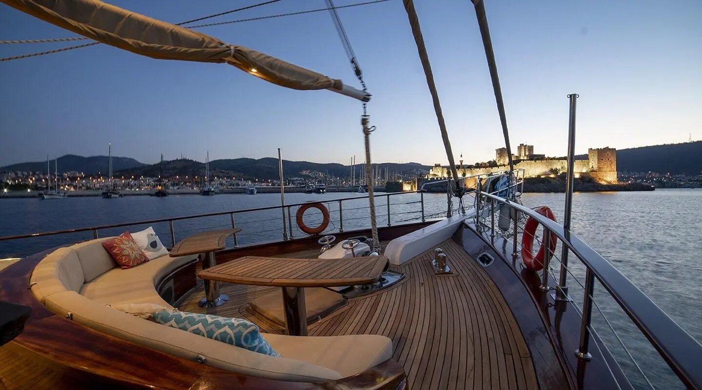 Arabella yacht deck at sunset with wooden railing and view of calm sea