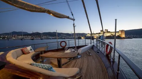 Arabella yacht deck at sunset with wooden railing and view of calm sea
