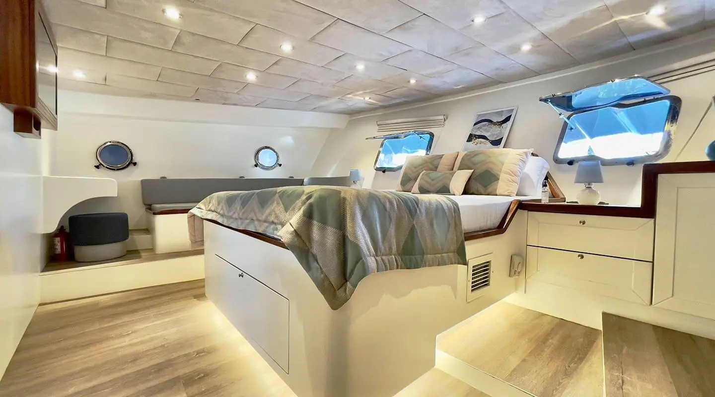 Derya Deniz yacht cabin with large bed, portholes, and warm lighting