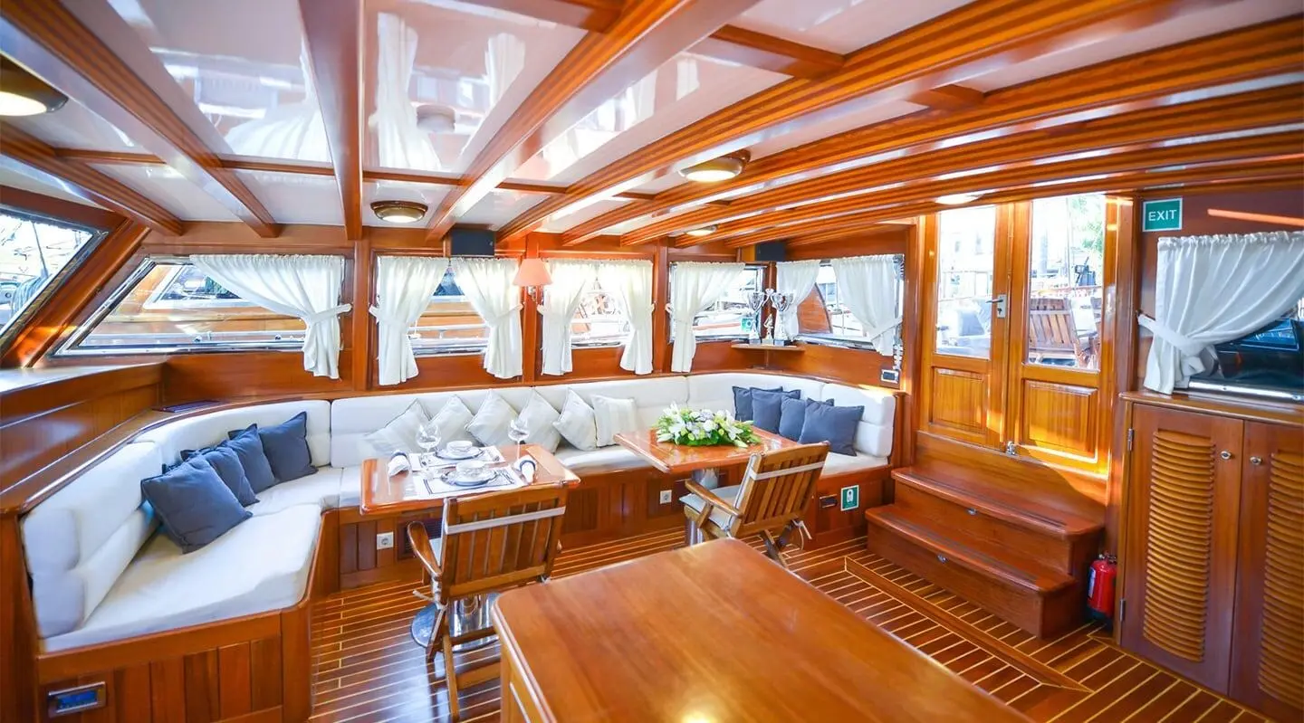 Ros Mare yacht with wooden deck and seating area at sunset harbor