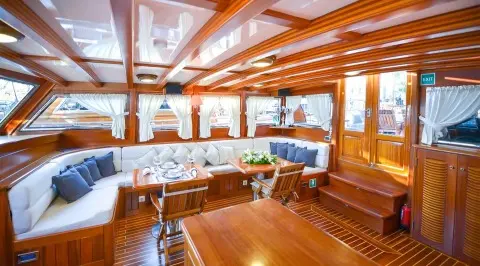 Ros Mare yacht with wooden deck and seating area at sunset harbor