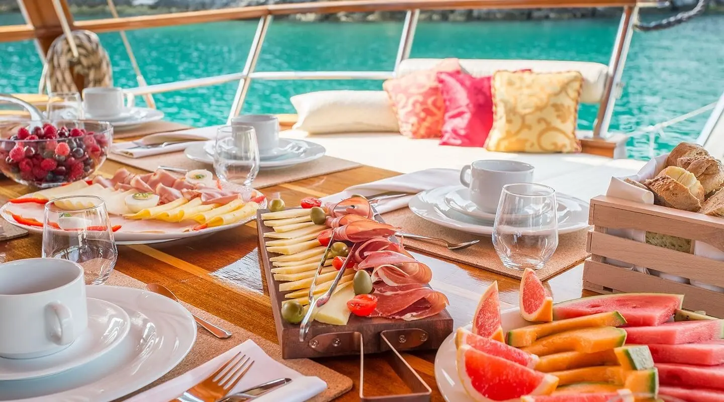 Gulet Altair on a sunny deck with dining setup and cocktails onboard