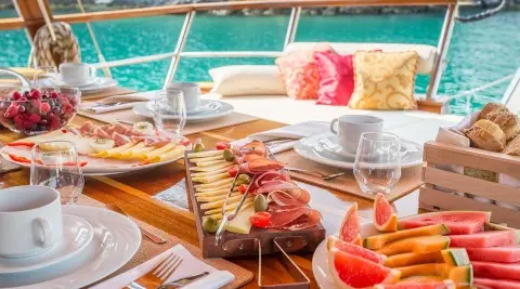 Gulet Altair on a sunny deck with dining setup and cocktails onboard