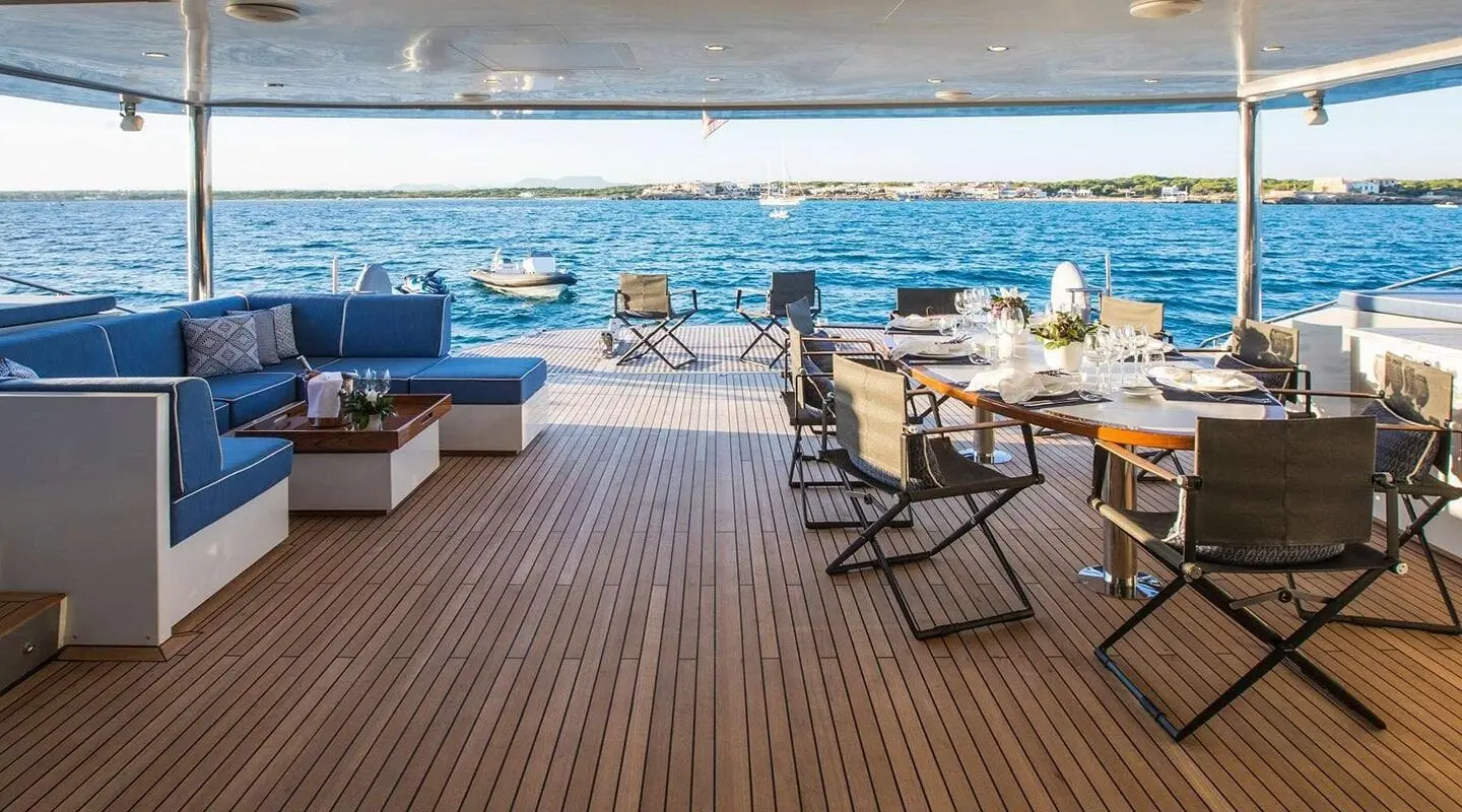 Cartouche yacht deck lounge with seating and sunbeds overlooking blue sea at sunset