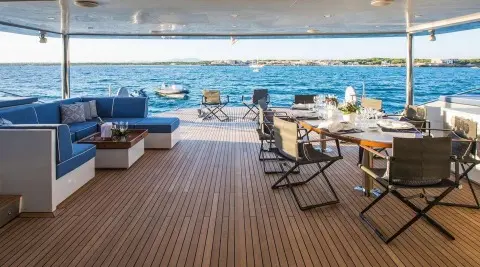 Cartouche yacht deck lounge with seating and sunbeds overlooking blue sea at sunset