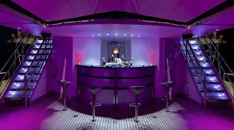 Running on Waves interior bar area with purple lighting and two staircases on either side