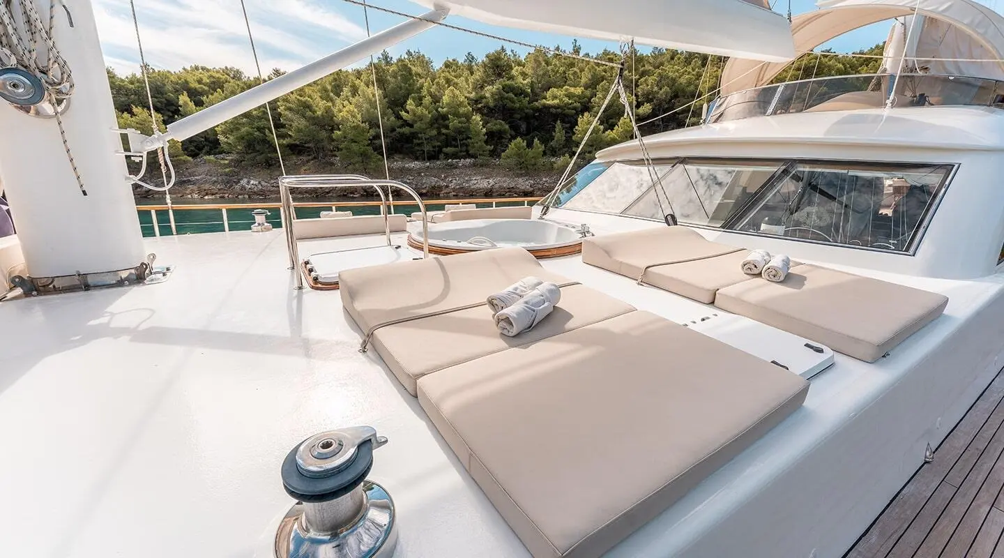 Alessandro I yacht deck with cushioned sunbeds on a calm sea at sunset