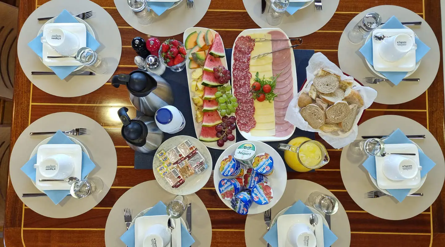 Top-down view of Mendula yacht dining setup with plates and fruit