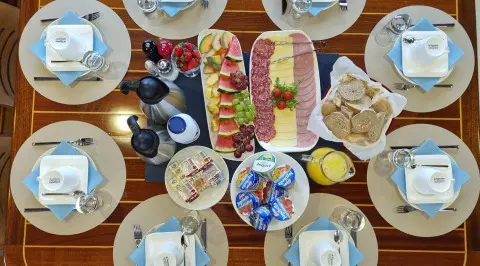 Top-down view of Mendula yacht dining setup with plates and fruit