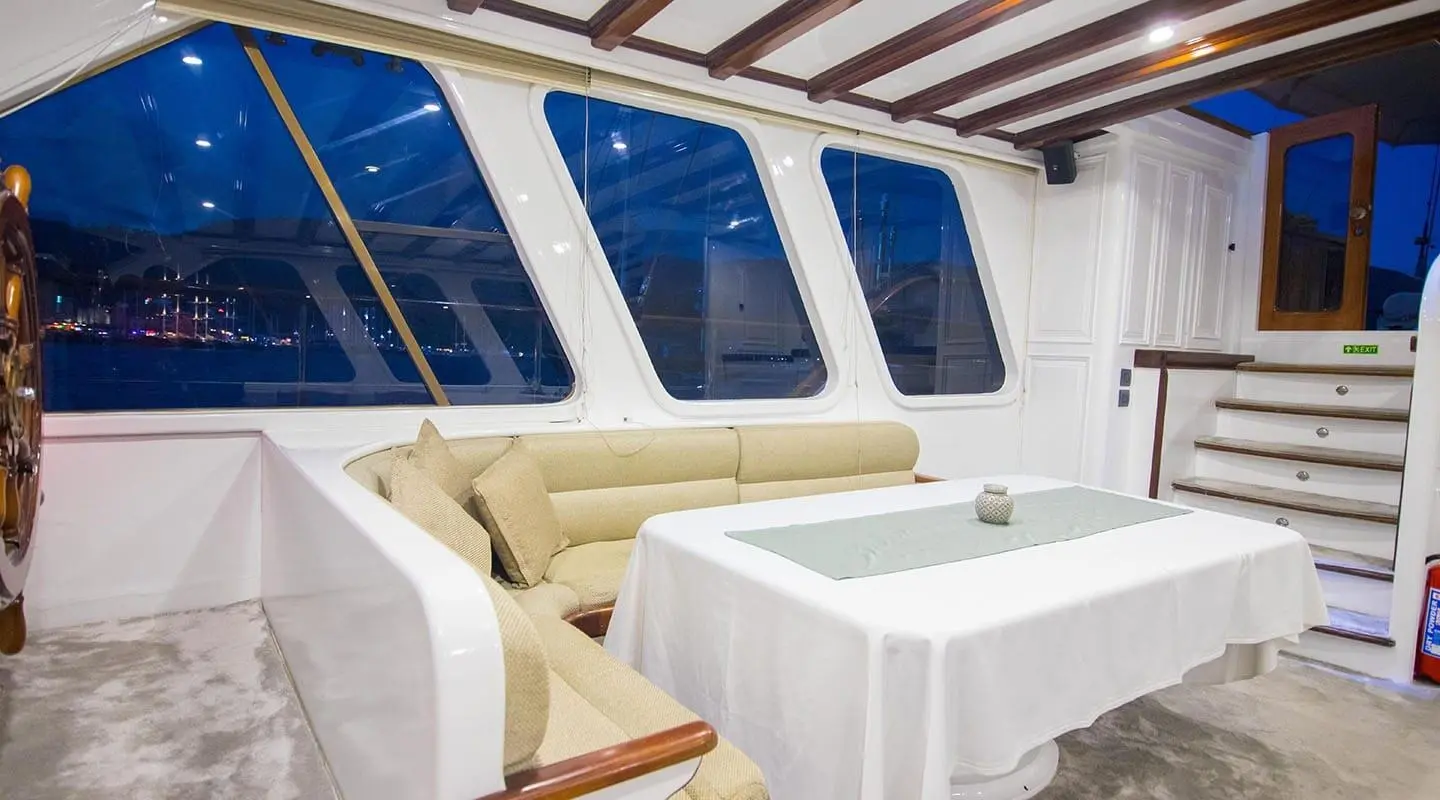 Grande Mare yacht interior with white seating and a table under a shaded deck at sunset