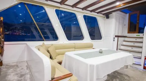 Grande Mare yacht interior with white seating and a table under a shaded deck at sunset