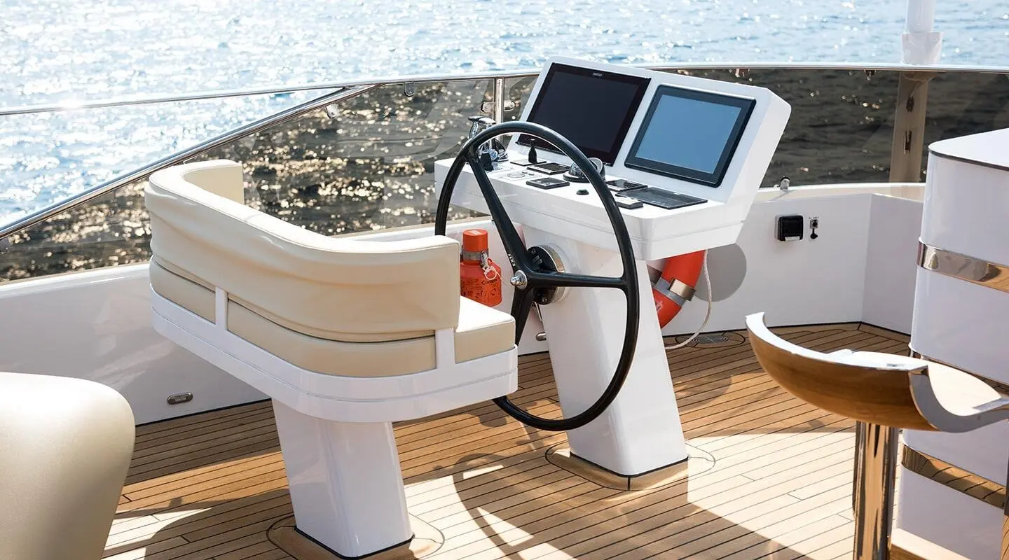 Open deck helm with steering wheel and navigation screens on a yacht