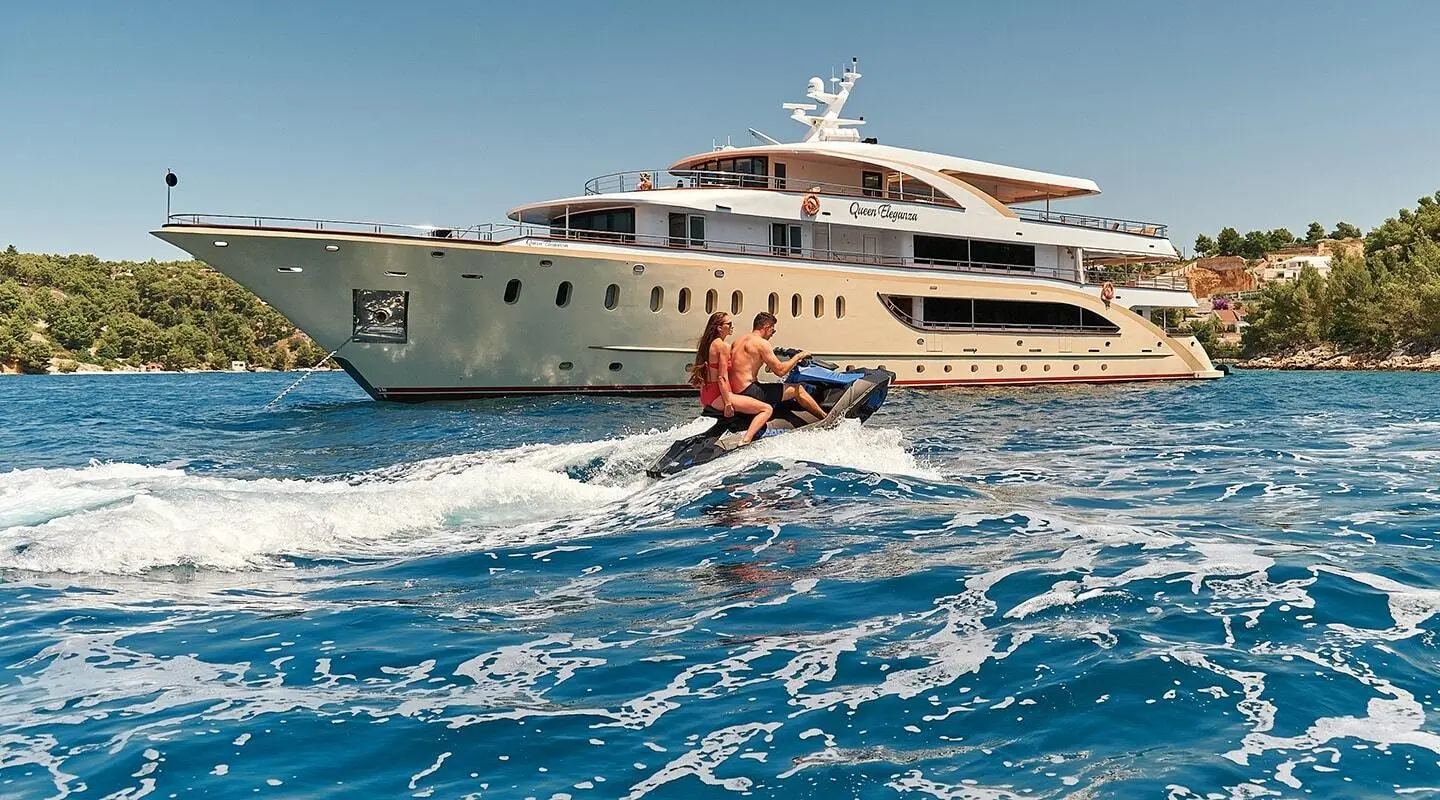 Queen Eleganza yacht on water with people engaging in water sports