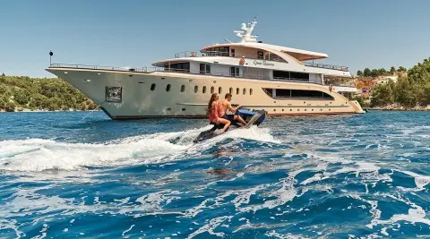 Queen Eleganza yacht on water with people engaging in water sports