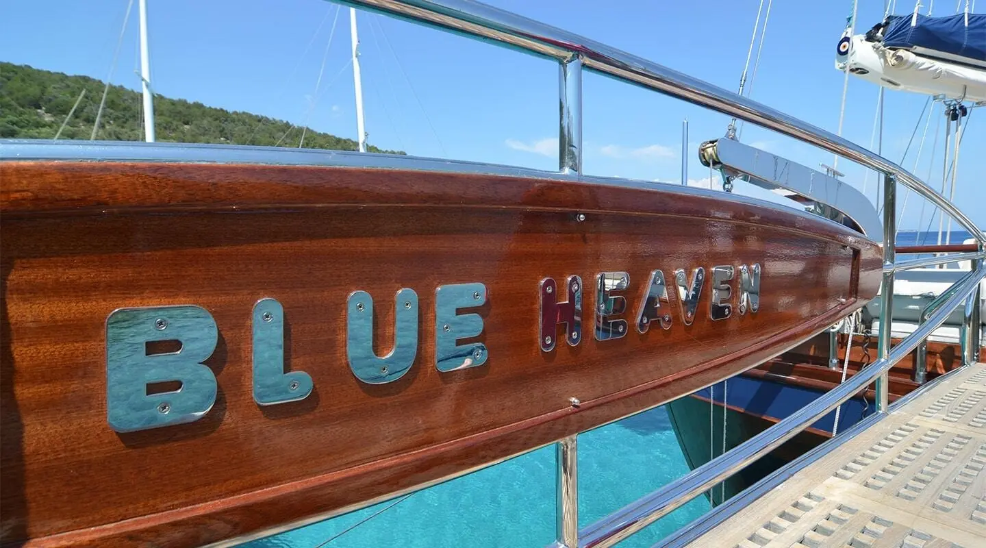 Blue Heaven yacht with turquoise water and wooden hull at sunset deck rail