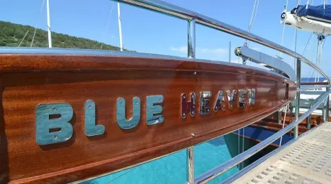 Blue Heaven yacht with turquoise water and wooden hull at sunset deck rail