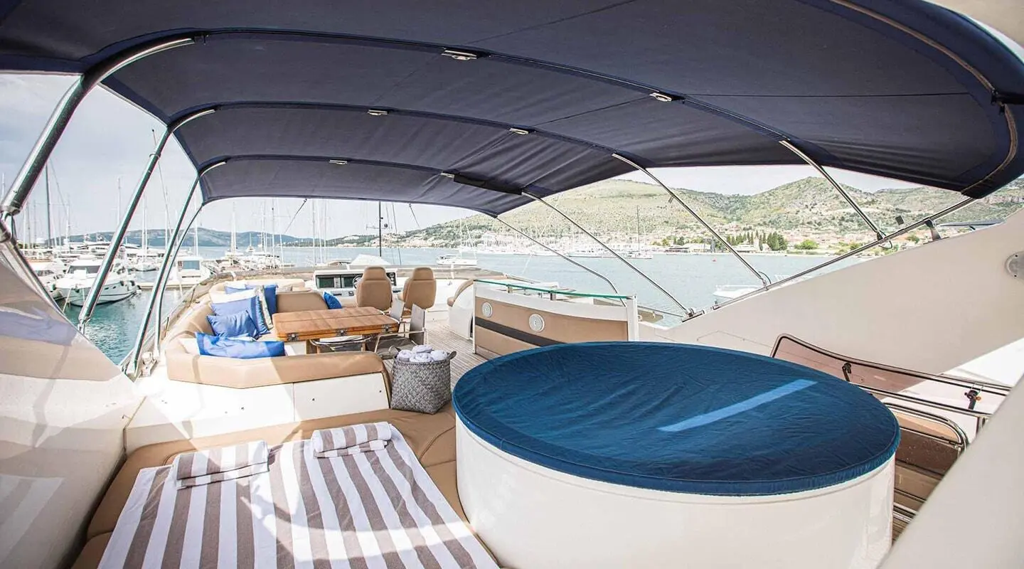Interior of a luxury yacht deck with striped seating and blue cushions, Under a curved white canopy