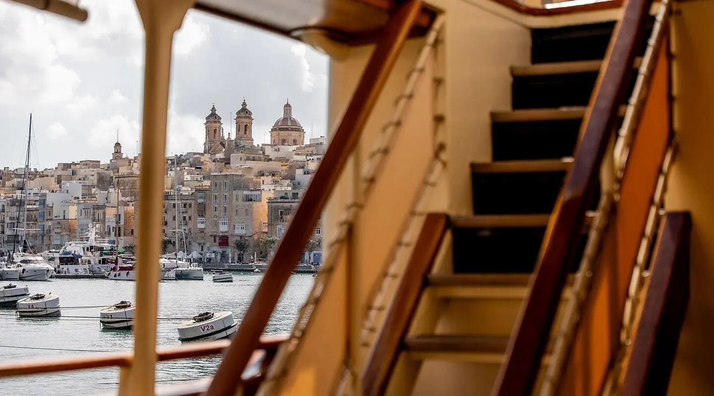 Deck view of Seagull II yacht with stairs and harbor skyline beyond