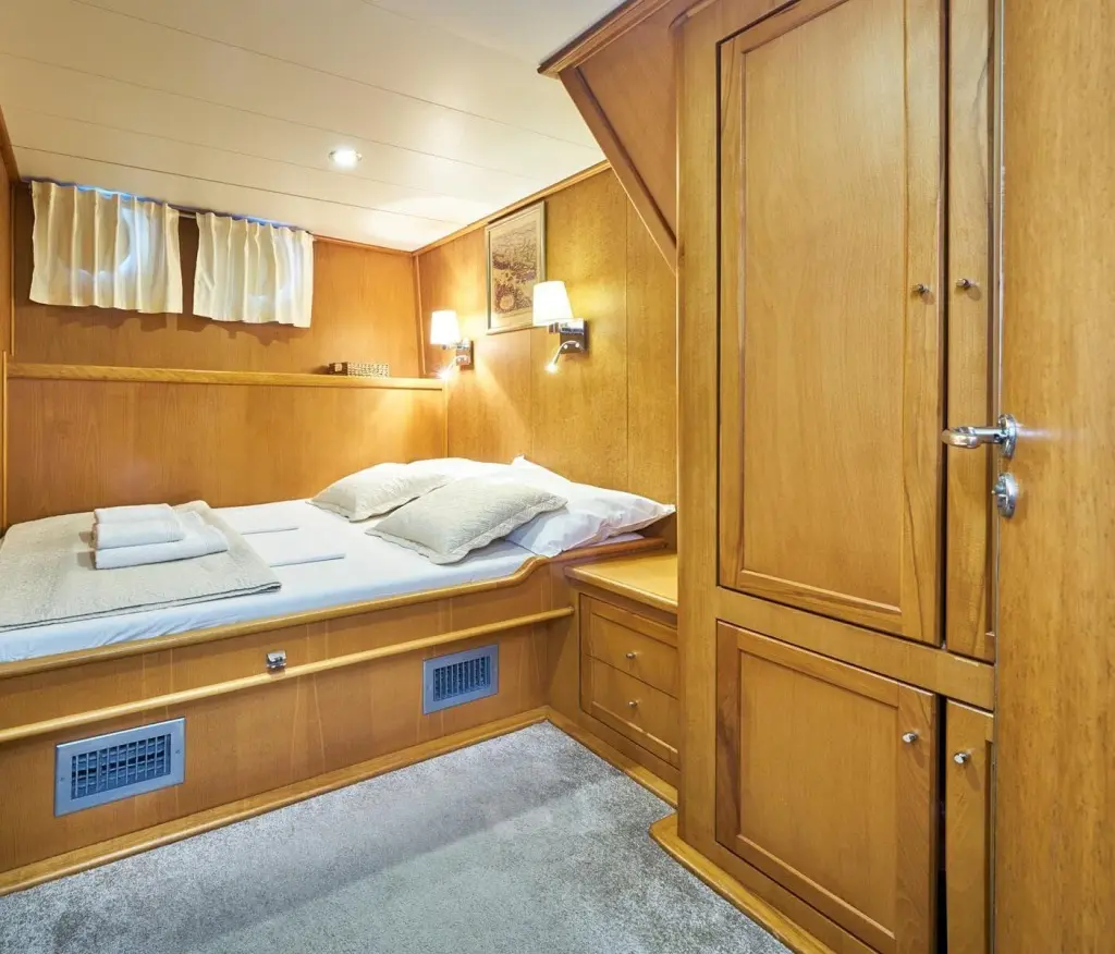 Morning Star yacht interior: cozy wooden cabin with bed, reading lamp, and built-in storage