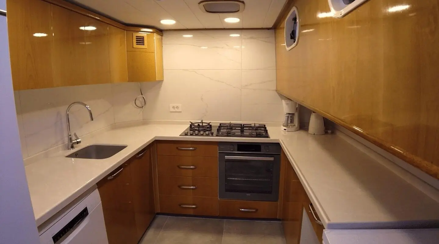 Maya yacht kitchen: wooden cabinets, stove, sink, and white countertops