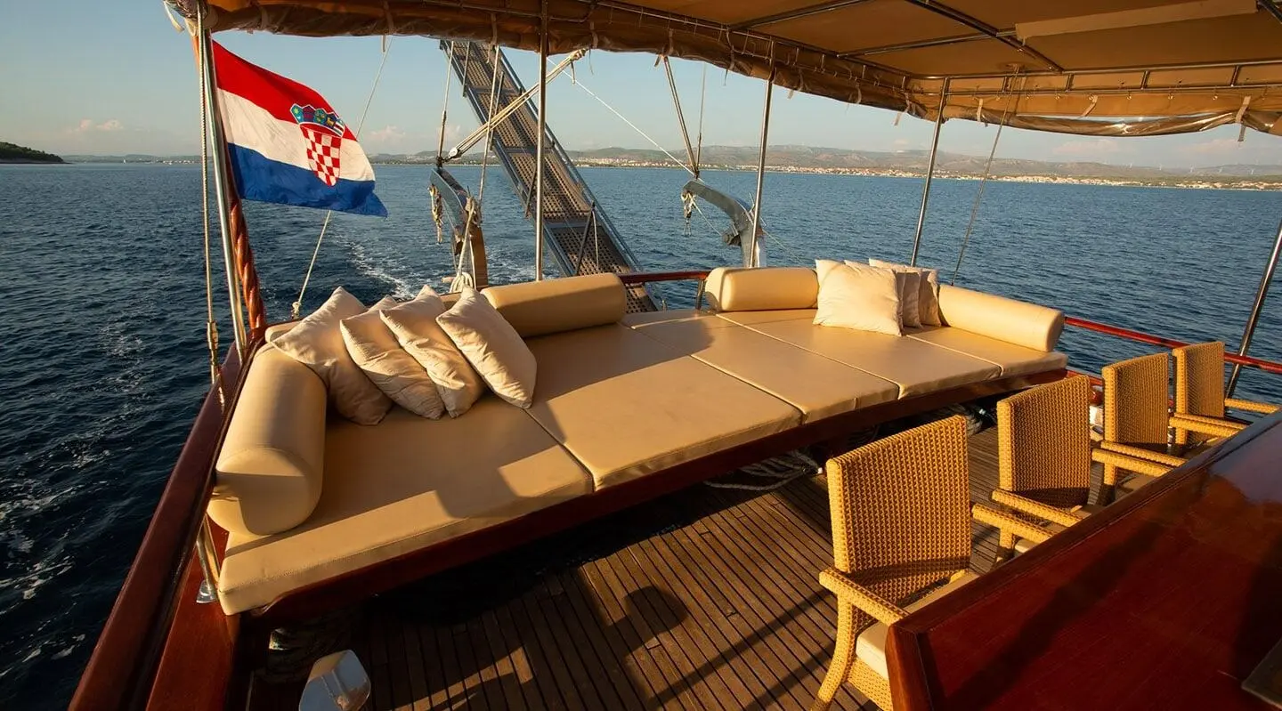 Sunset-lit luxury gulet deck with cushioned seating and wooden railings