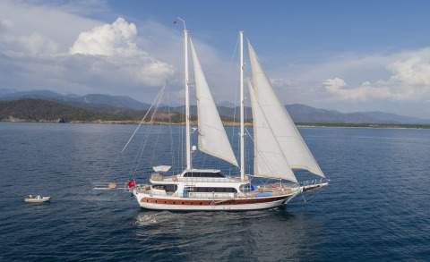 Kayhan 4 sailing yacht with white sails on calm blue sea and distant coastline