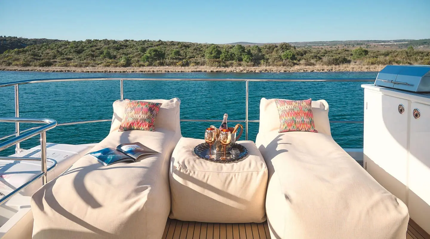 Sun loungers on a yacht deck with cushions while calm sea and horizon