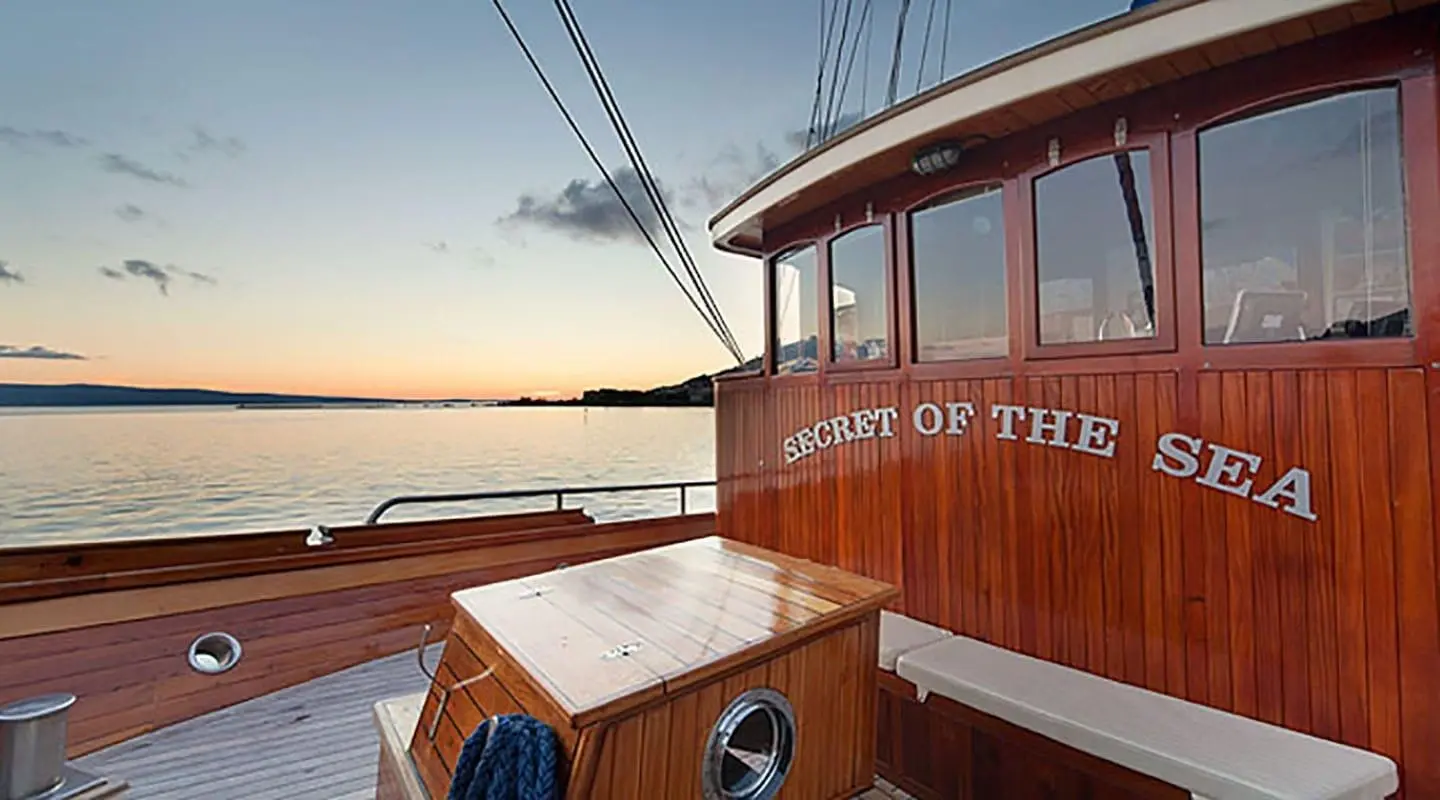 Sunset on a wooden yacht deck with rigging and calm sea horizon