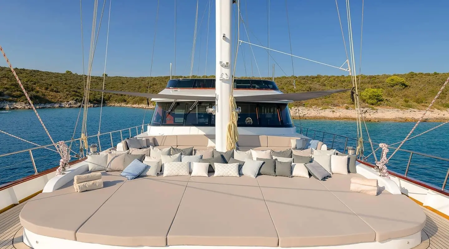 Lady Gita yacht bow seating area with cushions and railing under clear sky