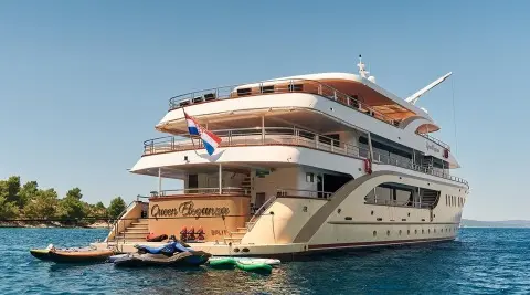 Queen Eleganza yacht anchored with people on deck and water sports boats