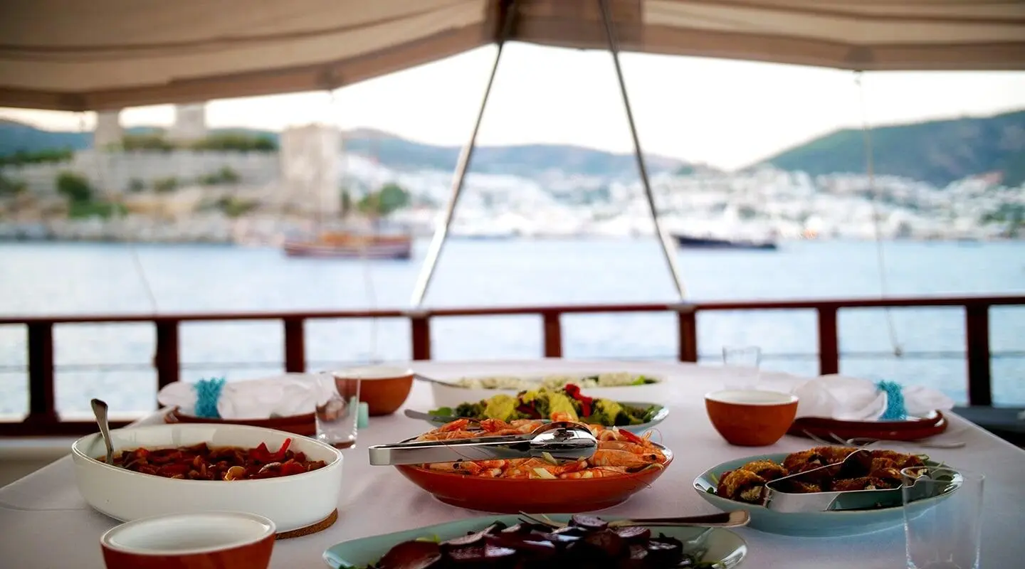 Overhead view from a yacht table with plates of fruit and beverages on Cobra King during sunset