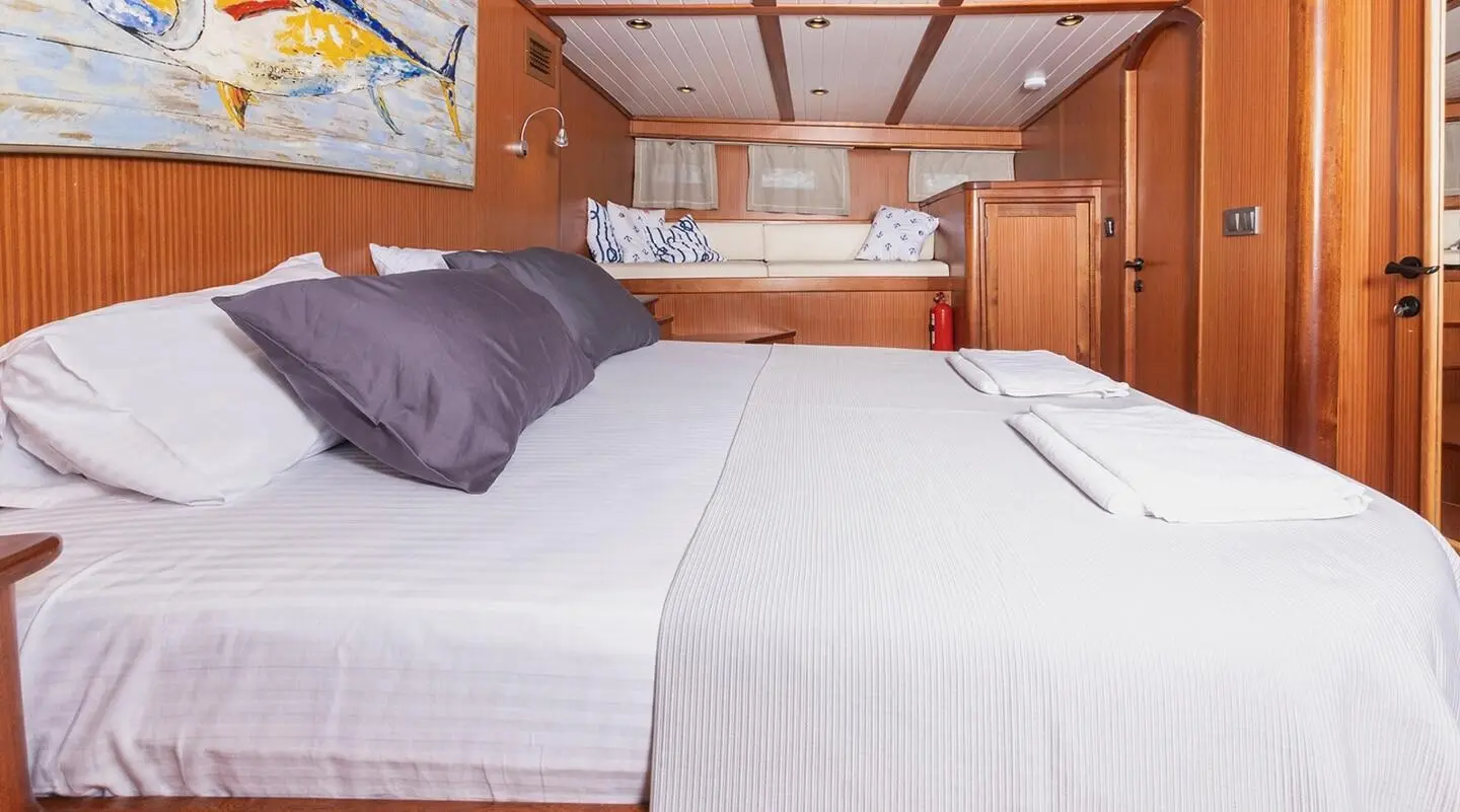 Interior of Bodrum Queen yacht with large bed, wooden cabinets, and porthole