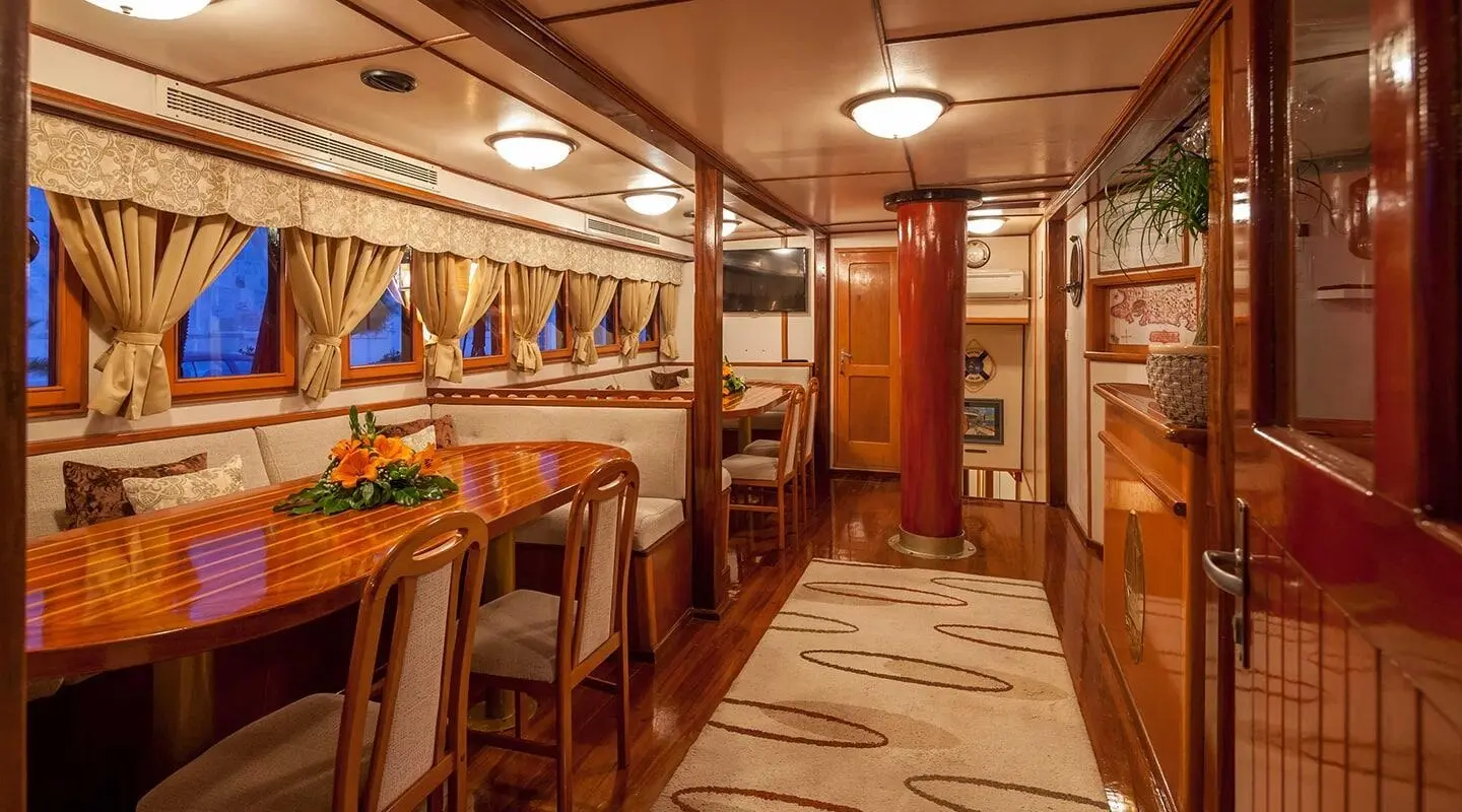 Romanca yacht charter interior with wooden panels, dining area, and warm lighting