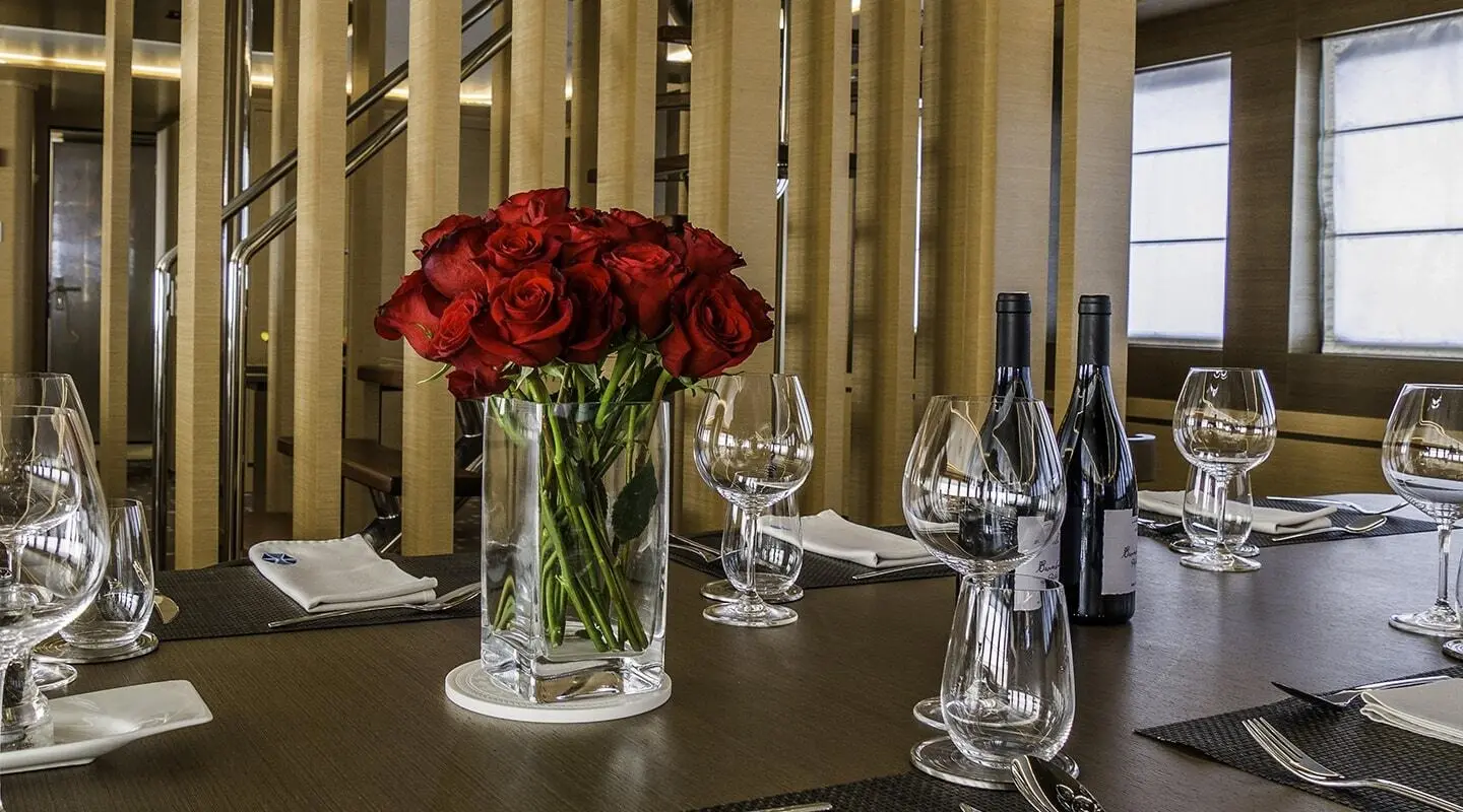Table setting with a glass vase of red roses centerpiece