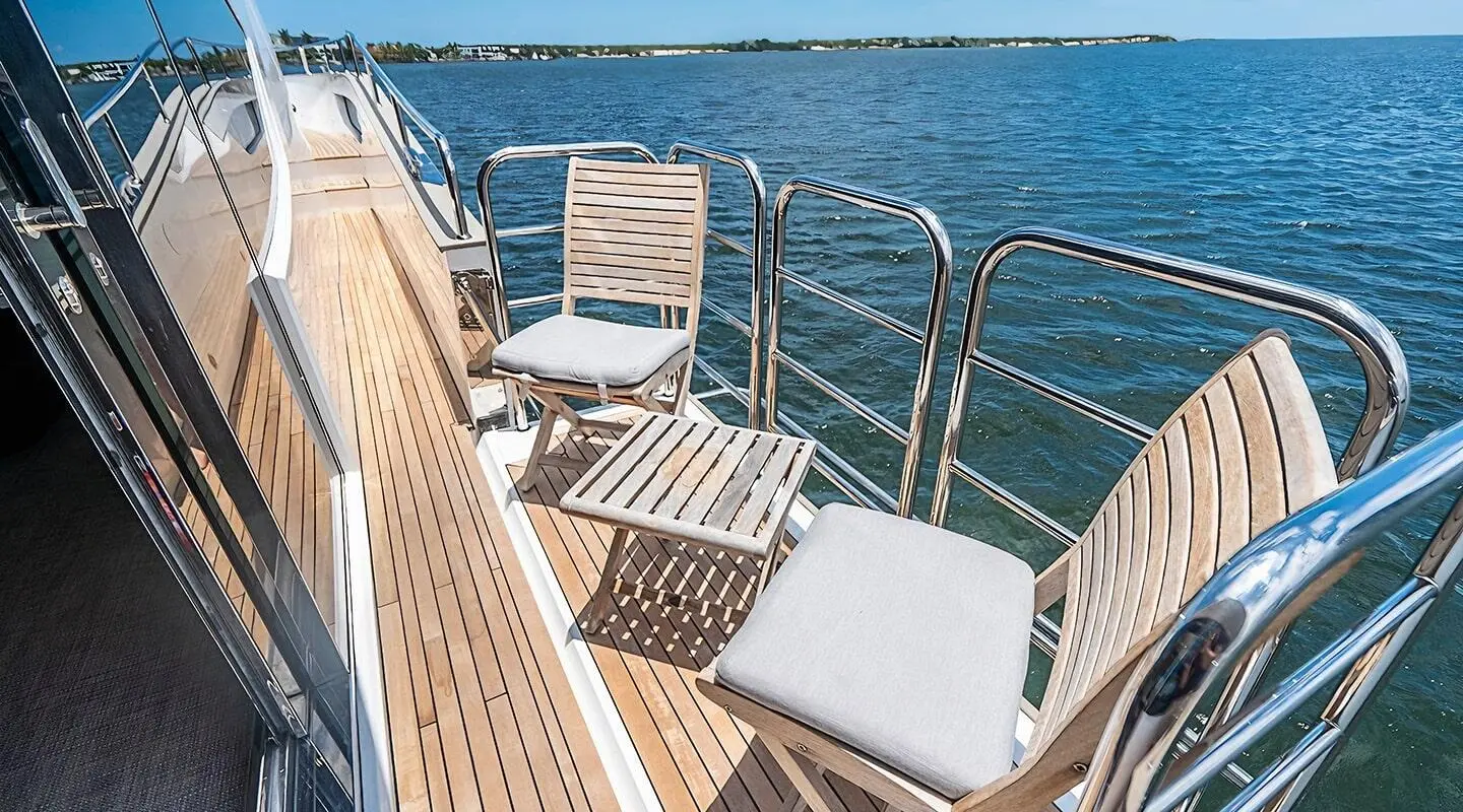 Quantum luxury yacht deck with white chairs facing blue sea at sunset