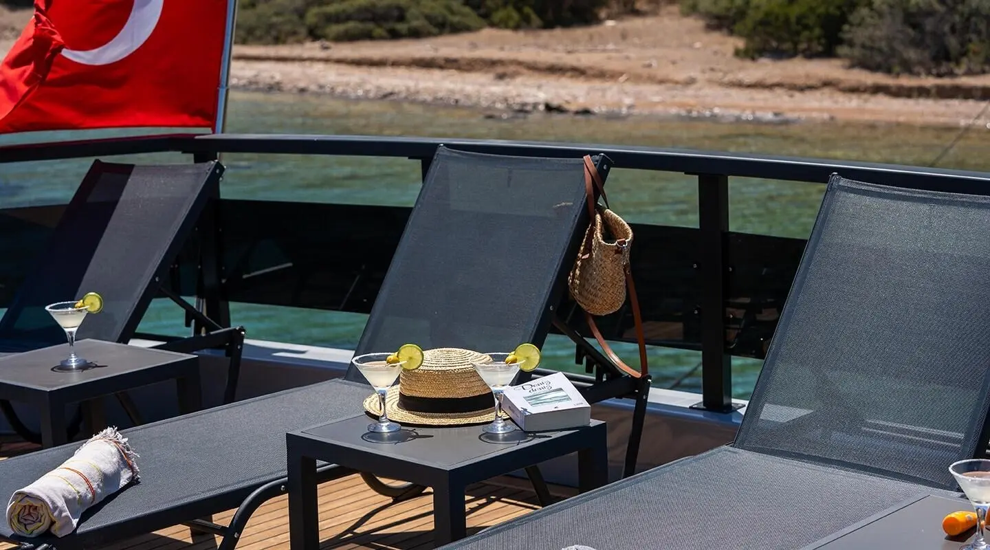 Calm Down yacht sunlounge with seating area and table overlooking water